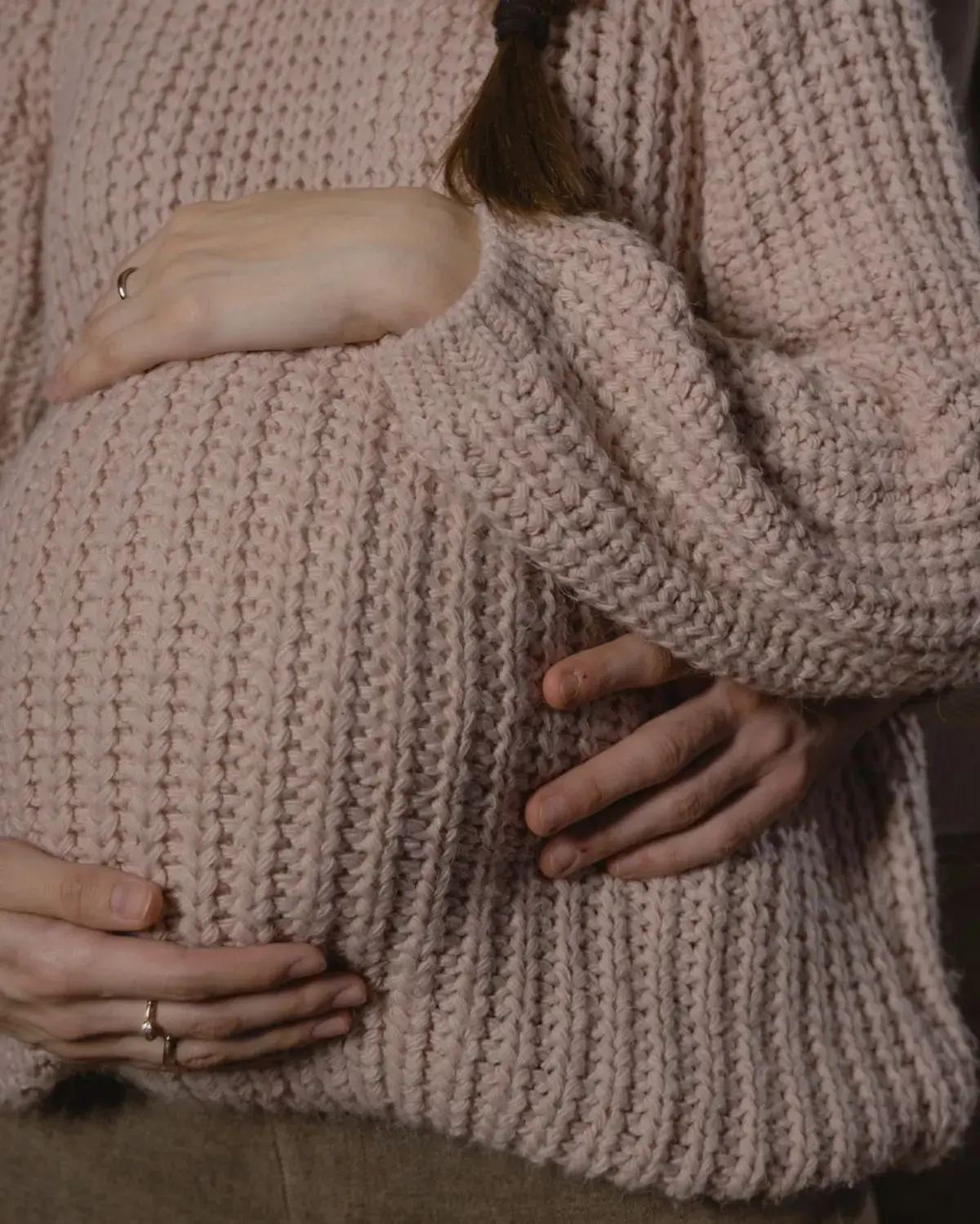 A pregnant couple gently cradling her belly together.
